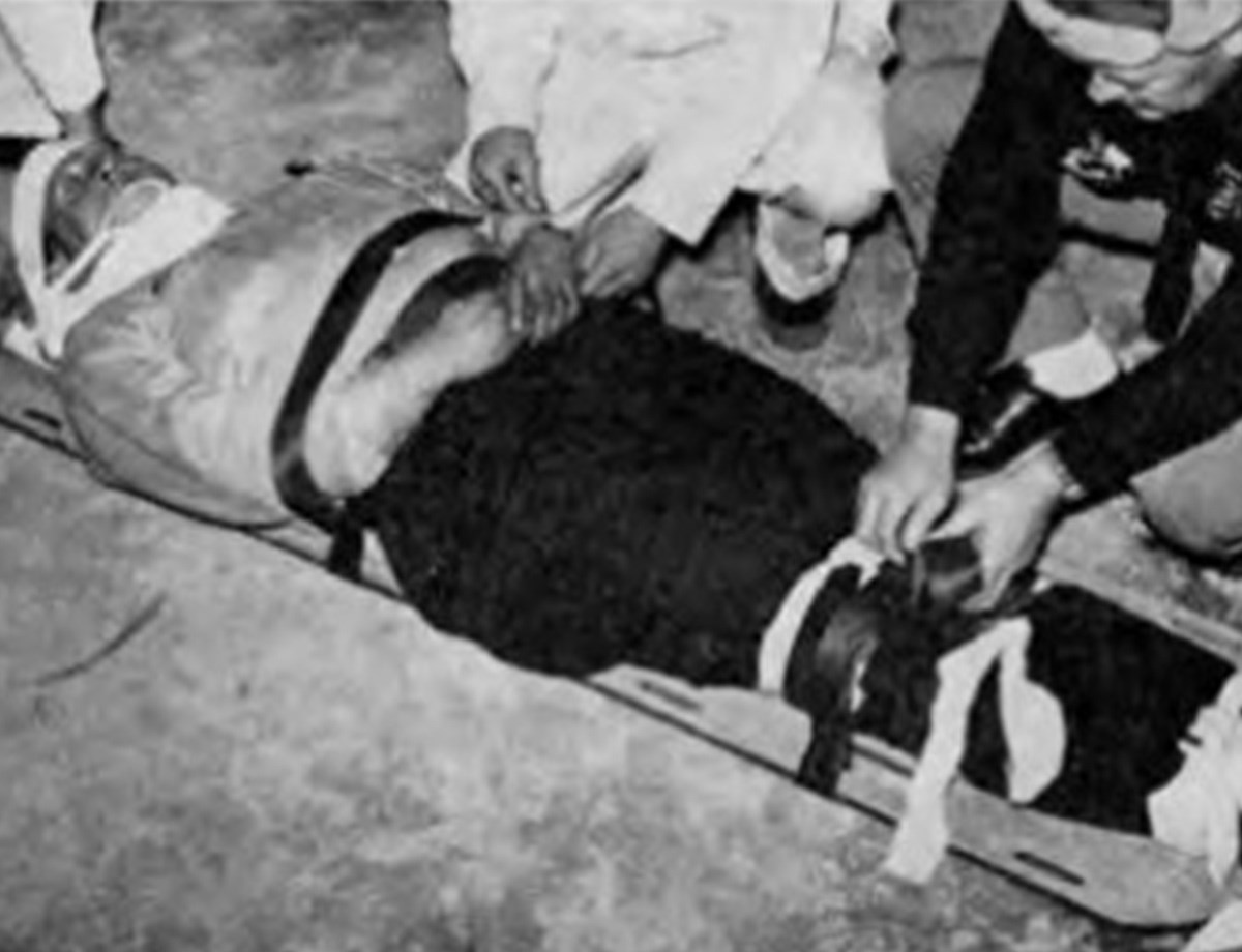 Death in a Ditch photo featuring injured man and rescuers.