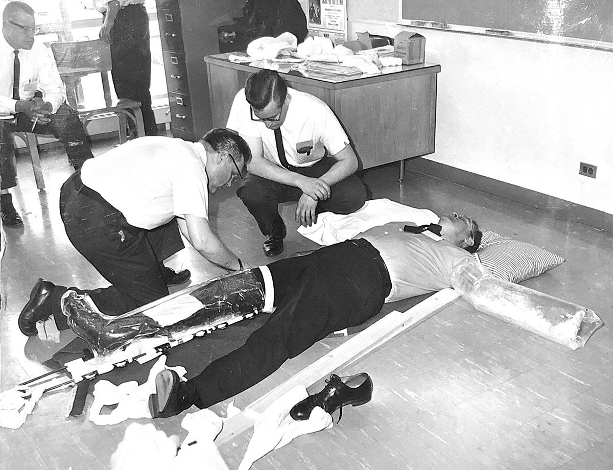 A mid-1960's training session for emergency responders depicting stabilization procedures for fractured limbs.